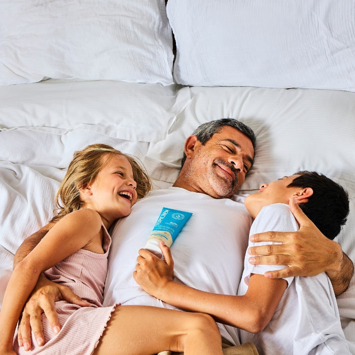 EEN-VADER-EN-ZIJN-TWEE-KINDEREN-LACHEN-OP-EEN-BED