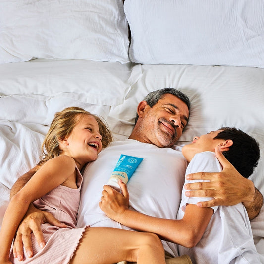 EEN-VADER-EN-ZIJN-TWEE-KINDEREN-LACHEN-OP-EEN-BED